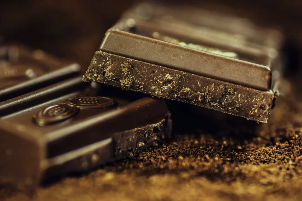 Carrés de chocolat noir posés sur de la poudre de cacao